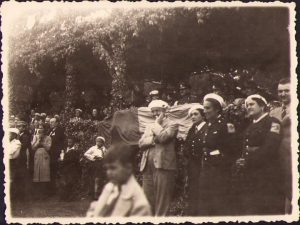 General Ion Carlaonț, comandantul Diviziei 11 Infanterie, în tribună alături de încă un general român și de alți ofițeri ai diviziei, notabilități și străjeri, asistând cel mai probabil la parada ținută cu ocazia zilei de 10 mai 1939 sau 1940 (anii în care I Carlaonț a fost comandantul diviziei) la Slatina