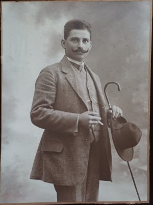 Bărbat cu baston, pălărie și țigară, studio Naschitz, Lugoj, fotografie de dimensiuni mari - pe spate reclamă Gabor Hecker, magazin de sticlă și de porțelan din Lugoj